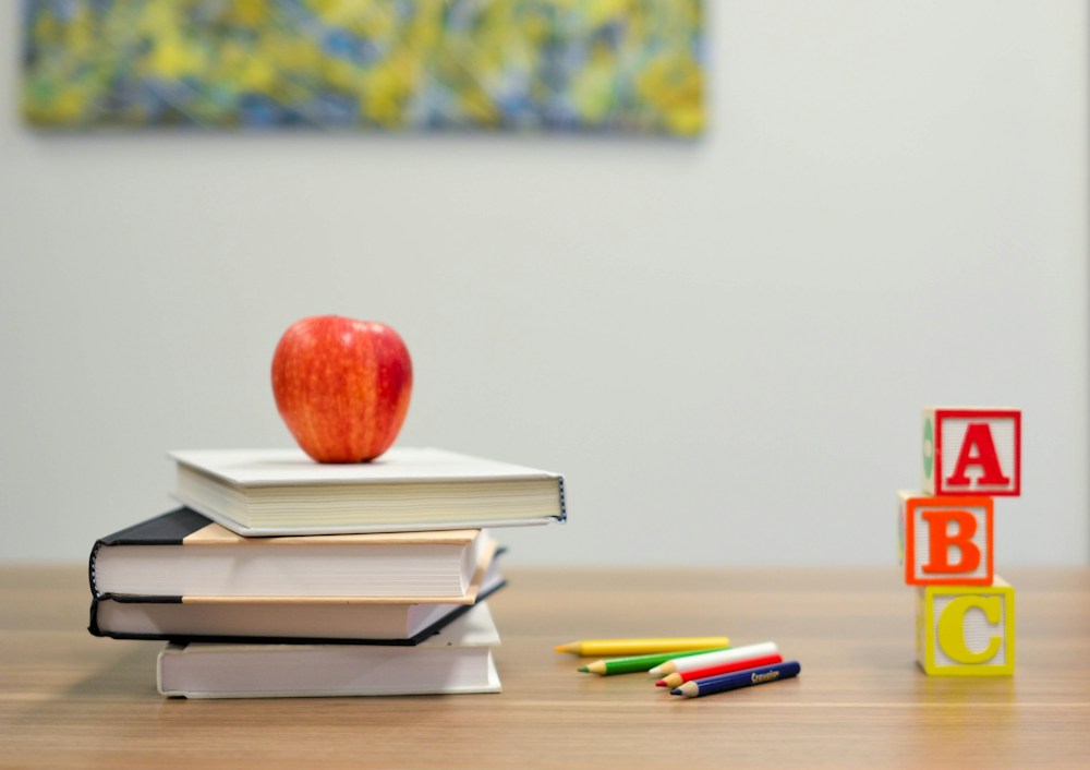 Books, pencils and an apple on a classroom desk